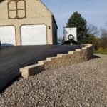 Asphalt driveway paved in front of a shed with a slope and gravel