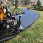 CMI Paving professionals work on paving a residential asphalt driveway