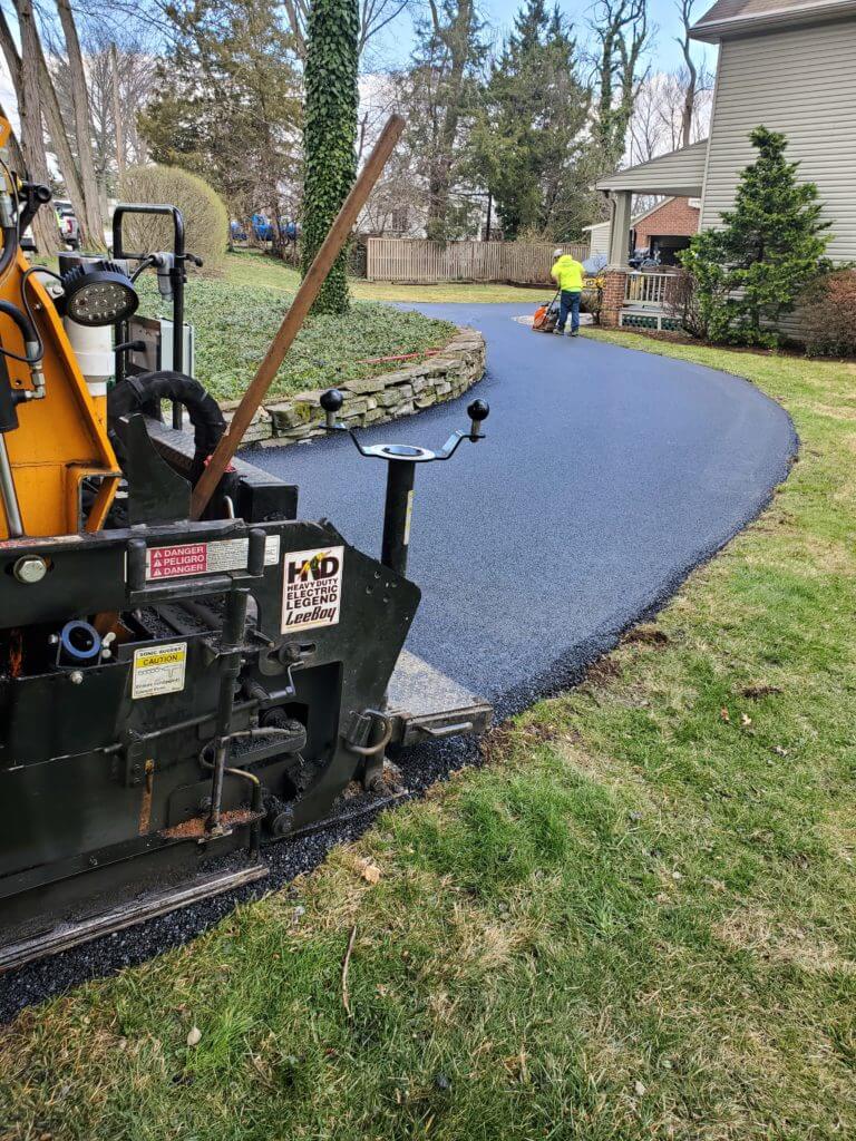 CMI Paving professionals work on paving a residential asphalt driveway